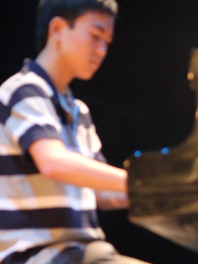 Aluno tocando piano em apresentação da escola
