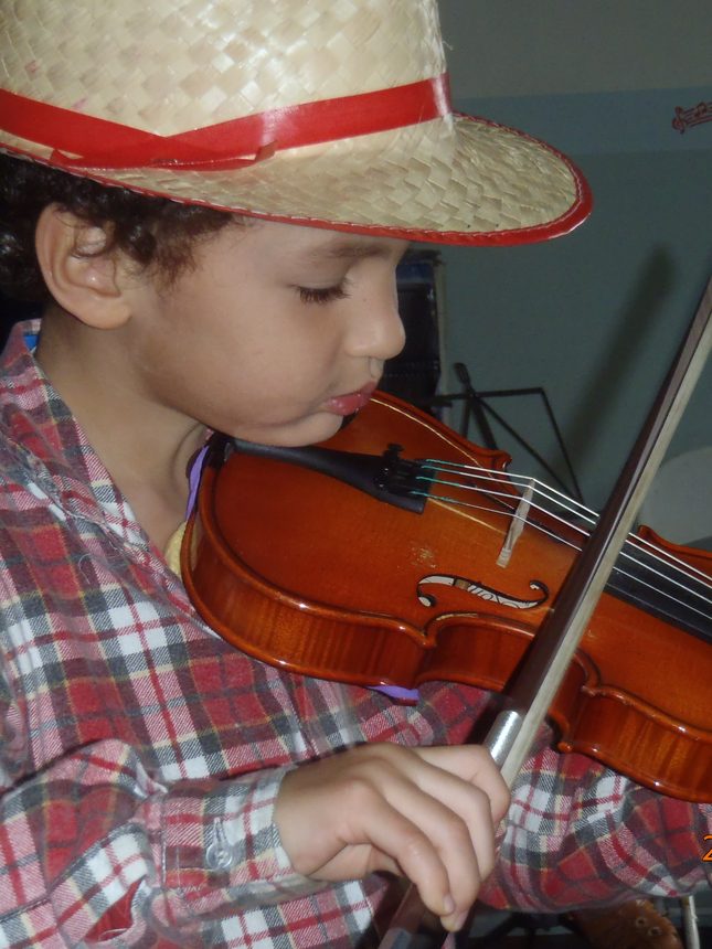 Aluno tocando violino em sala de aula da TaCaTum